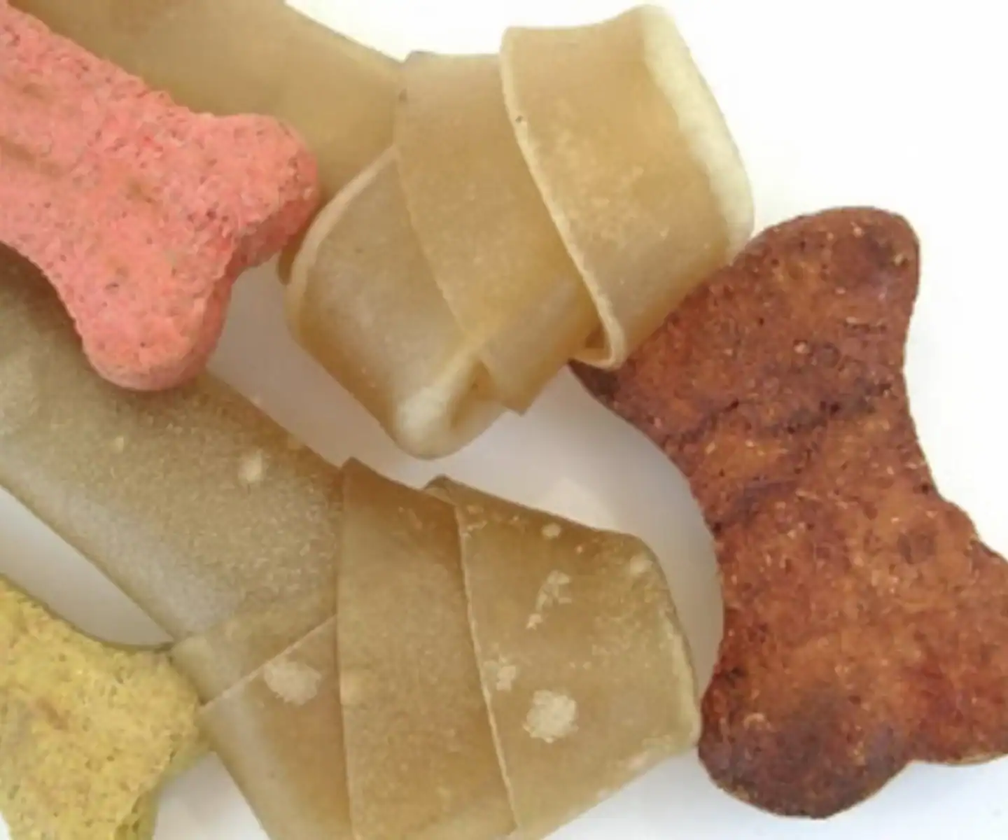 Assorted dog treats in various shapes and flavors on a white surface.